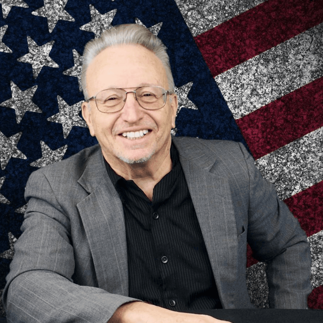 Smiling man in glasses and suit against a stylized American flag background.