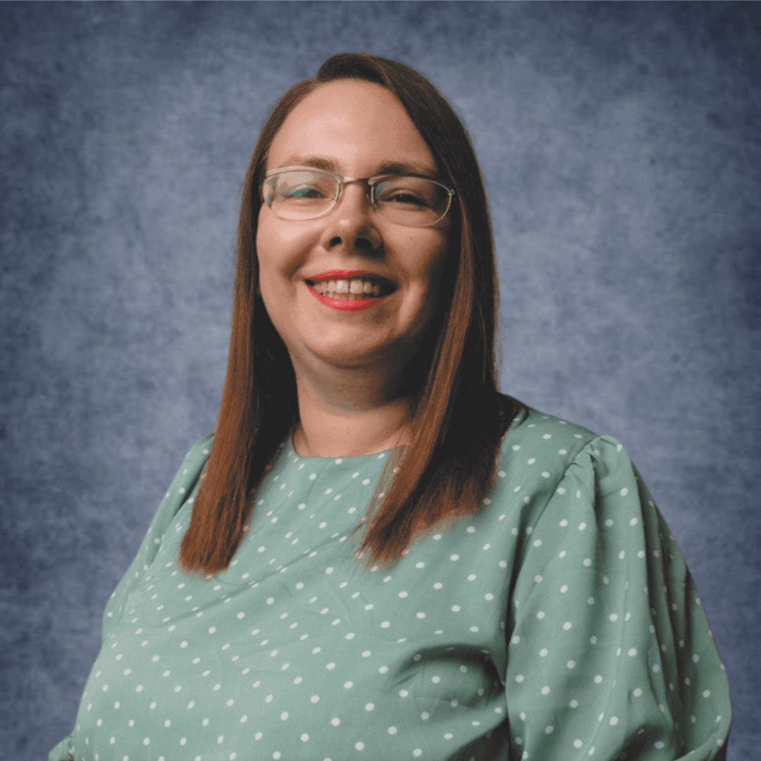 Individual wearing a green polka-dot blouse with brown hair against a textured blue background.