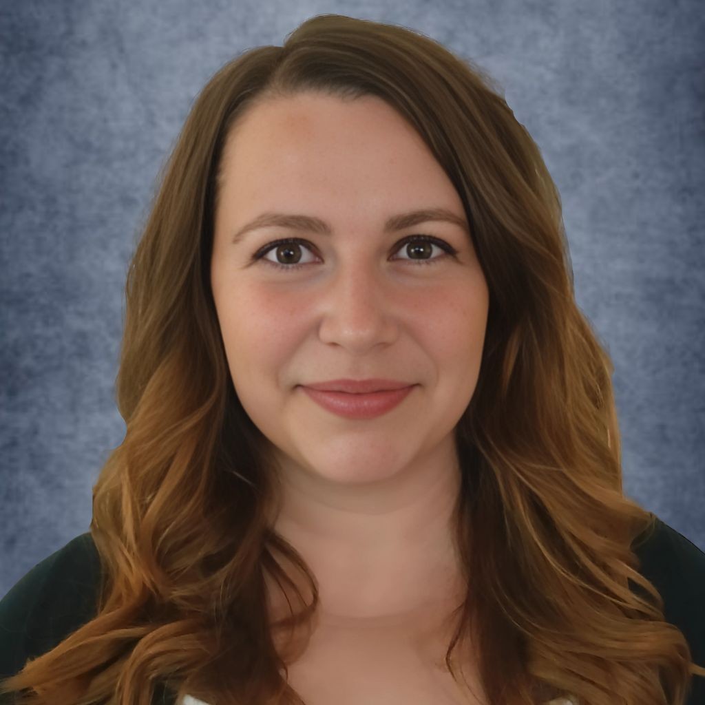 Smiling woman with long brown hair against a gray textured background.